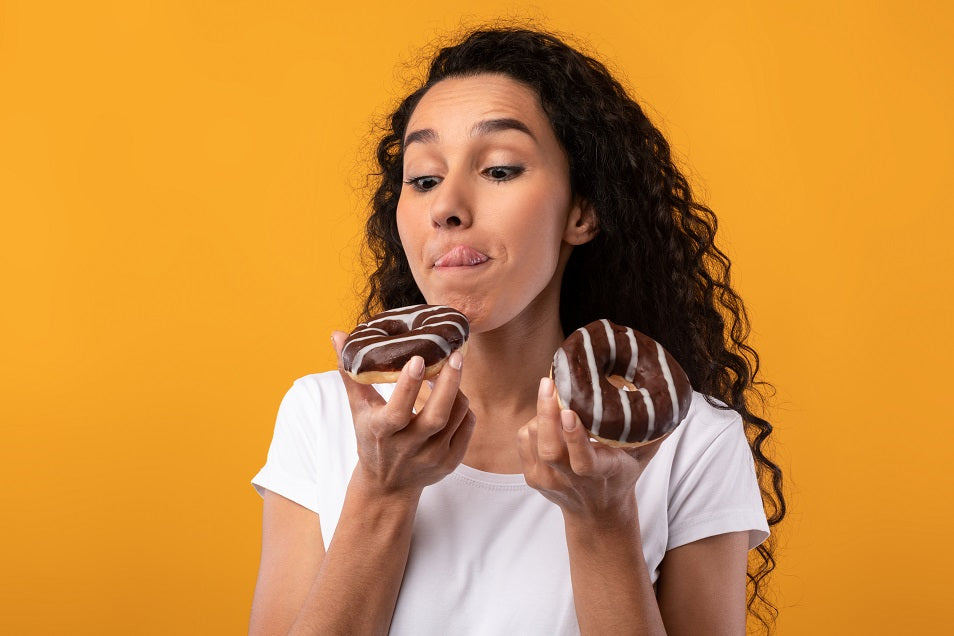 woman holding 2 chocolate donuts licking lips