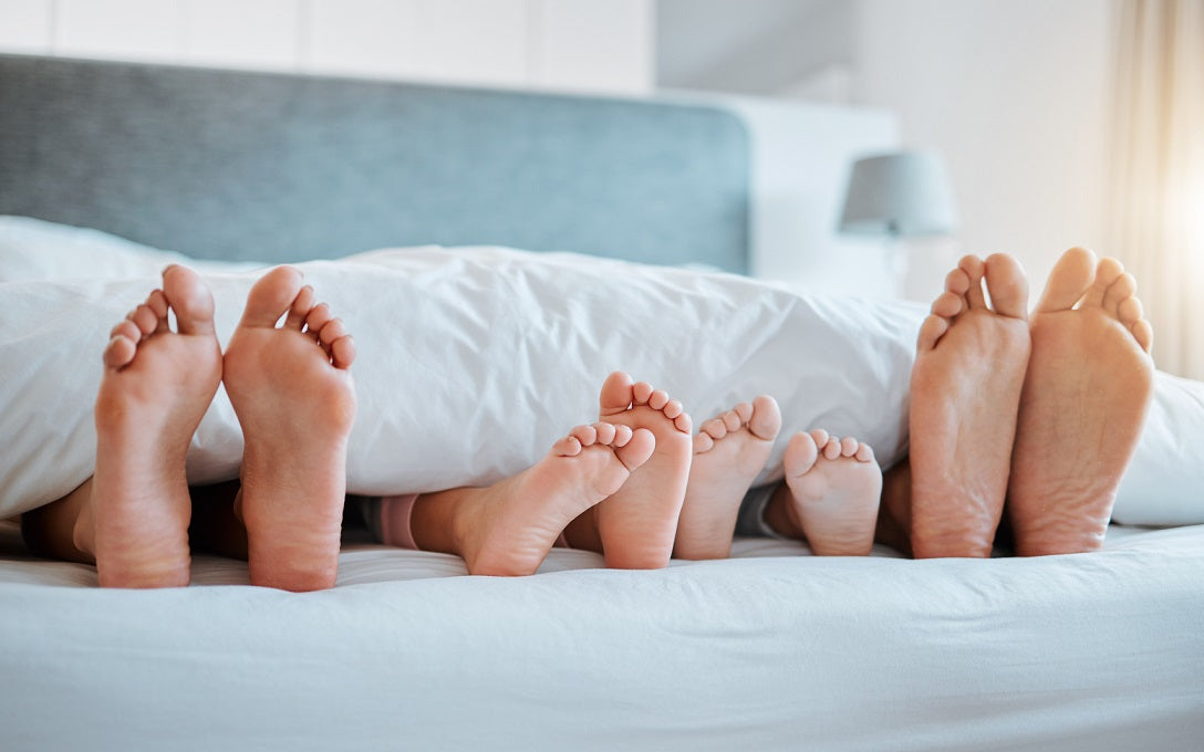 Family in bed with feet sticking out from under duvet