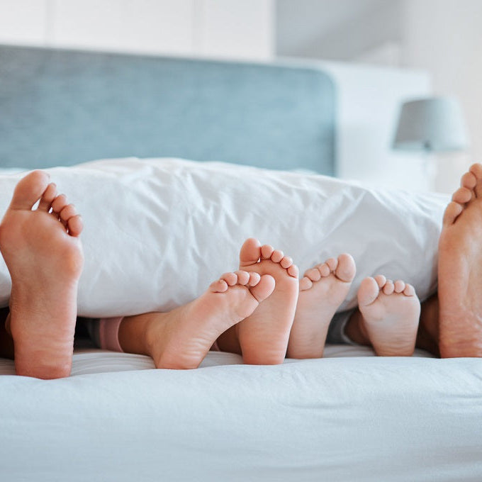 Family in bed with feet sticking out from under duvet