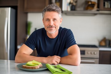 Healthy man at kitchen bench eating breakfast