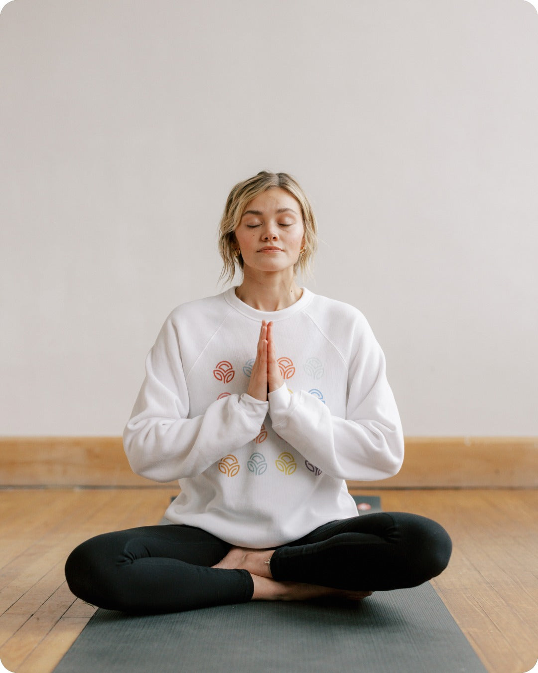 Young women inside on mat meditating in a yoga position