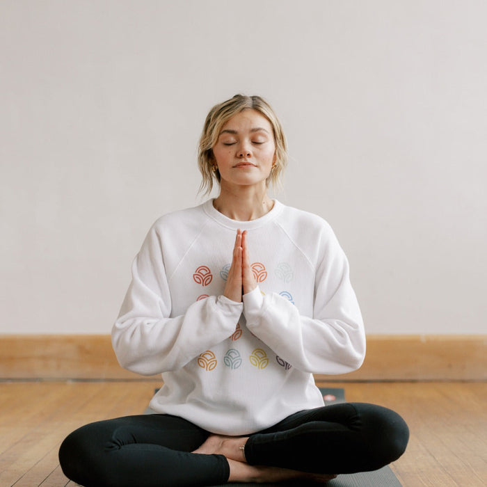 Young women inside on mat meditating in a yoga position