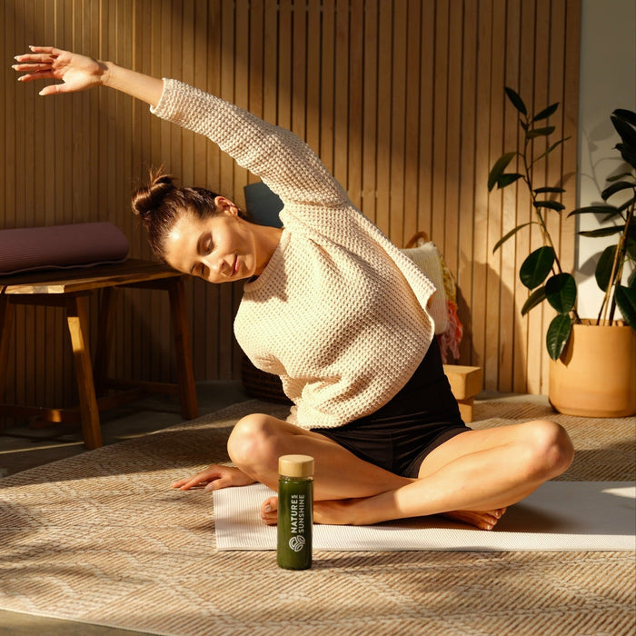 Woman on floor doing stretches with Nature Sunshine drink bottle