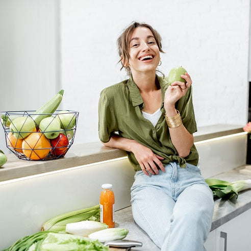 Woman sitting in kitchen eating fruit