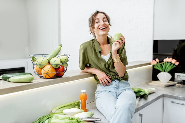 Woman sitting in kitchen eating fruit