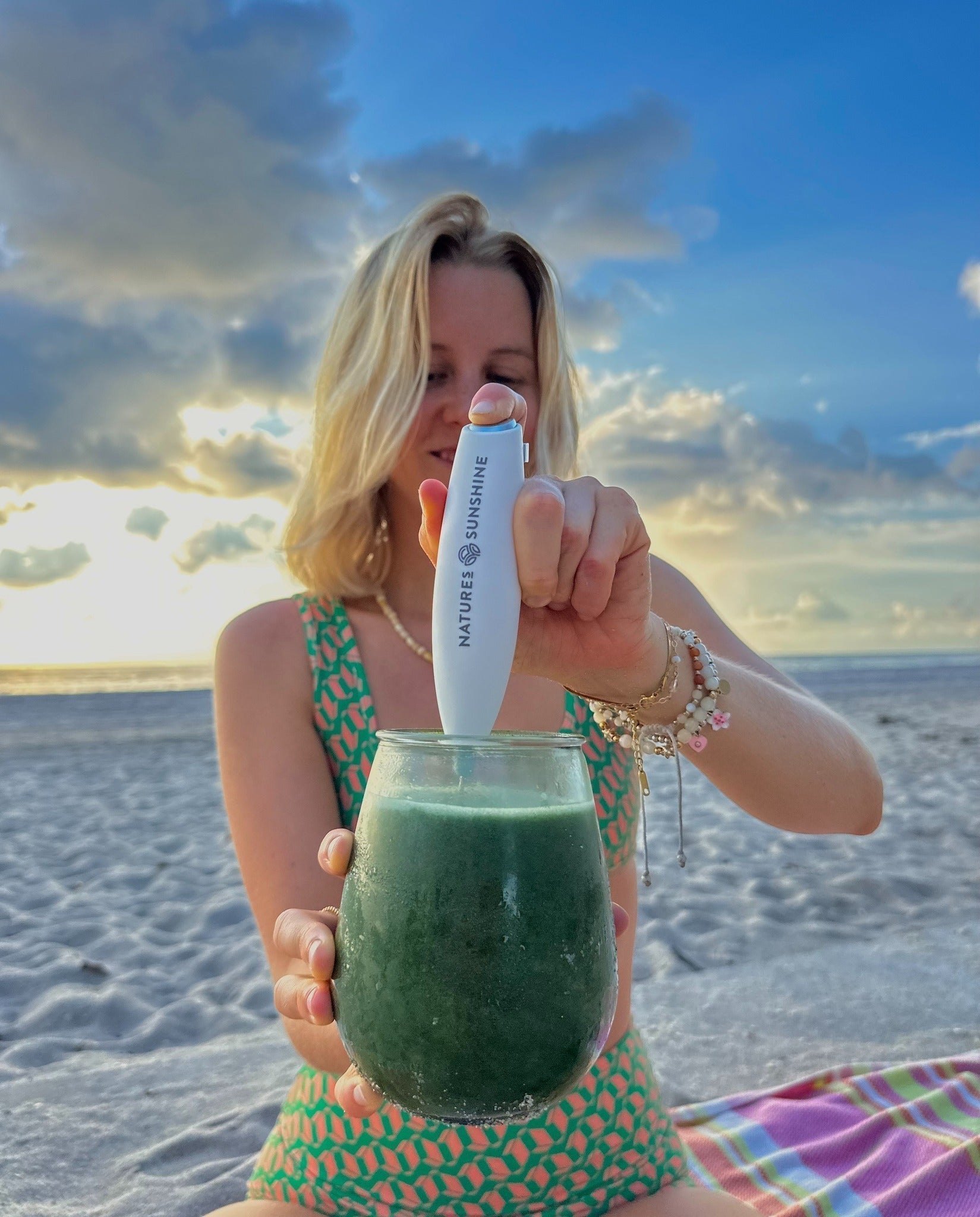 woman in swimsuit on beach mixing natures sunshine chlorophyll drink