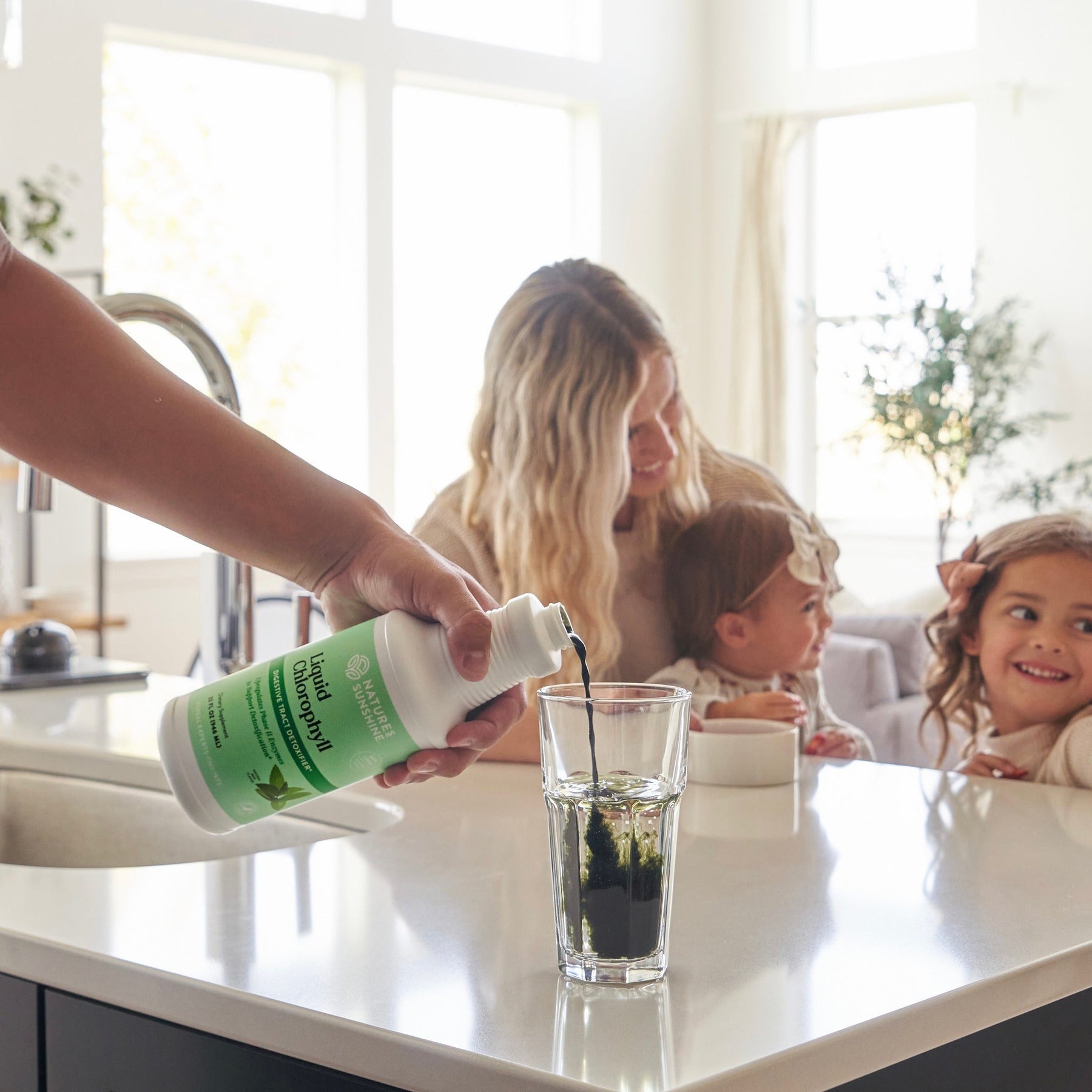 Family around kitchen bench drinking Natures Sunshine liquid chlorophyll