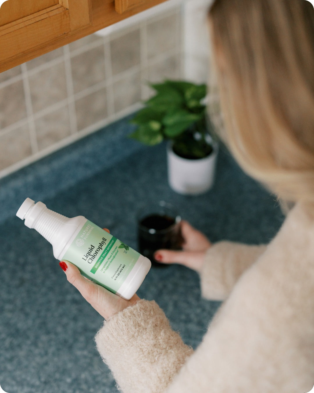 woman in kitchen holding bottle of natures sunshine liquid chlorophyll