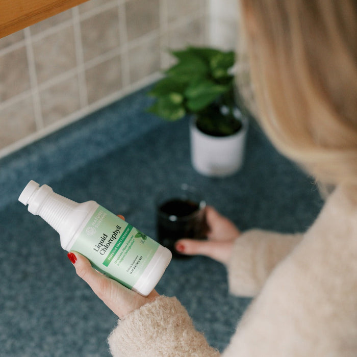 woman in kitchen holding bottle of natures sunshine liquid chlorophyll